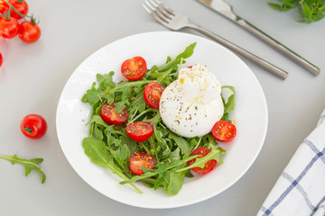 Fresh Salad with Italian burrata cheese, arugula, cherry tomatoes and olive oil. Healthy eating. Selective focus 