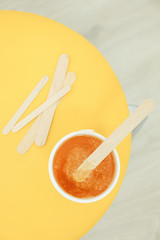 Liquid yellow paste for shugaring on yellow background, top view