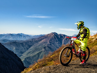 Active man riding downhill mountain bike and looking at mountains