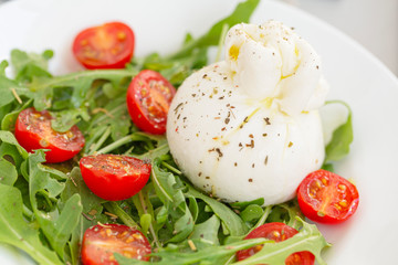 Fresh Salad with Italian burrata cheese, arugula, cherry tomatoes and olive oil. Healthy eating. Selective focus 
