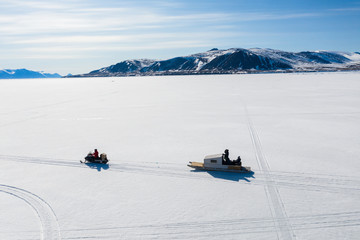 Aerial drone photo of tourists travelling by Qamutiik on the sea ice near Sirmilik National Park in Nunavut, Canada