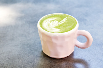 Vegan green tea matcha with oat milk with latte art in white cup on concrete table. With place for text.