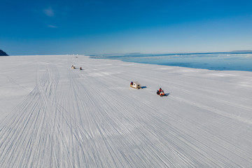 Aerial drone photo of tourists travelling by Qamutiik on the sea ice near Sirmilik National Park in Nunavut, Canada