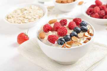 Tasty oatmeal porridge with raspberries, blueberries and nuts in bowl