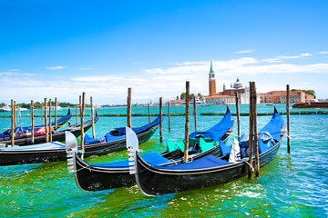 Fototapeta na wymiar Gondolas and bright turquoise water of canal. Grand Canal in Venice, Italy. Sunny summer vacations. Beautiful landscape with bright colors. 