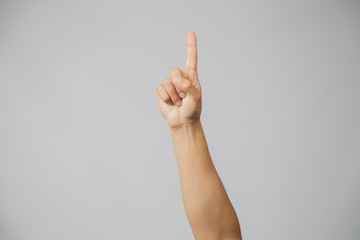 Man's hand with number one, hand raising index finger up in studio with gray background