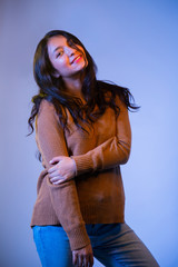 Hispanic woman portrait with colored lights in studio- young girl smiling playing with her hair