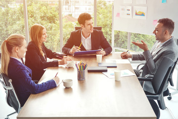 Group of business people discussing business in a meeting room with one empty chair.