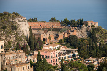 Fototapeta na wymiar Beautiful panorama from mountain top to a small mediterranean sicilian town, Taormina, in warm sunset with the sea in the background, Sicily, Italy