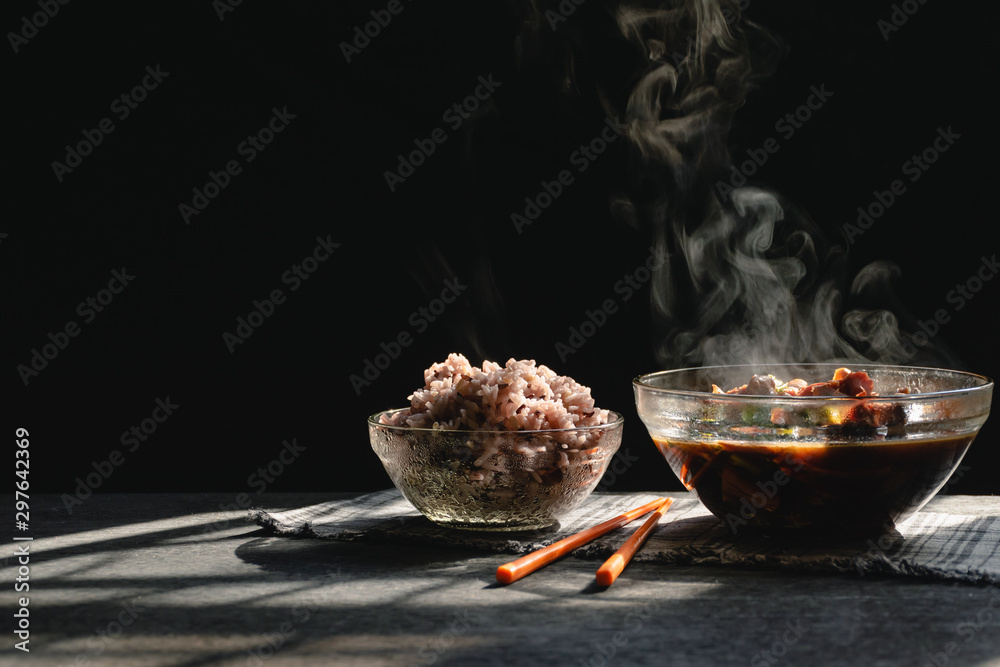 Wall mural Steam from Boiled stew and rice in a bowl on wooden table and black background,Morning nature light,Riceberry has high in antioxidants Reduce risk of cancer, Suitable for people who are losing weight.