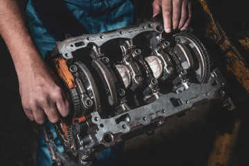 Hands of auto mechanic and disassembled engine, closeup. Car maintenance.