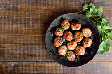 Fried cutlet in frying pan over wooden background with copy space