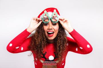 Studio portrait of young woman with dark skin and long curly hair wearing tight santa claus hat and...