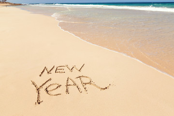 Inscription NEW YEAR on sandy beach