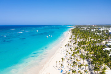Aerial view from drone on tropical coastline with coconut palm trees, sunbeds and boats floating in...