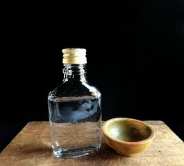 Bottle of brandy with clay cup on black background. typical alcoholic drink of Guatemala