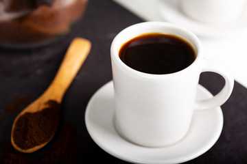 A coffee cup and a spoon spilling coffee powder