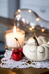 autumn and winter cozy table decoration with candle, small apples and white baby boo pumpkins