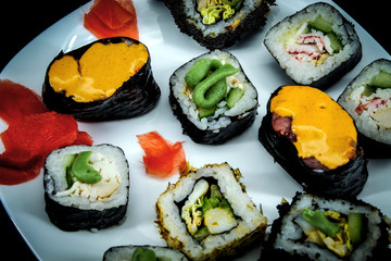 On a black background on a white plate a little fresh rolls