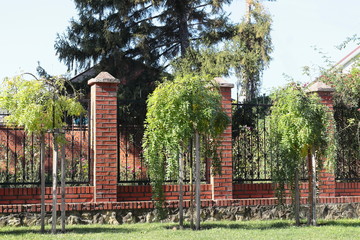 Obraz na płótnie Canvas fence of red bricks on the background of green trees