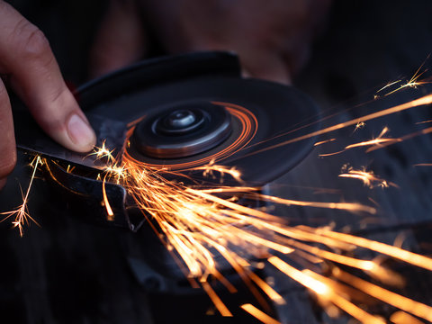 Man Sharpen Axe By Grinder In The Dark With Sparks