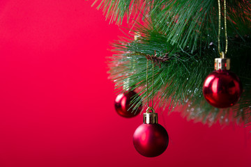 Christmas pine branch with red balls close-up on a red background
