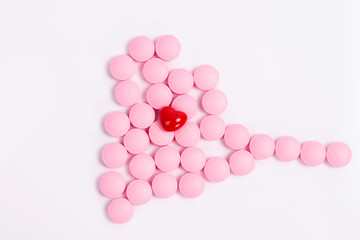 Pink pills on a white background with a red heart. Heart pills