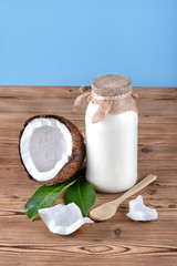 Coconut milk in the bottle on wooden rustic table , blue background . Healthy nutrition concept 