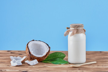 Coconut milk in the bottle on wooden rustic table , blue background . Healthy nutrition concept 