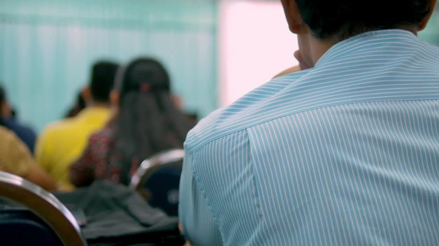 Asian people were listening to the training in the meeting room by the speaker using the projector screen for the lecture.