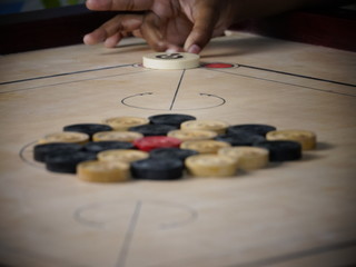Side view of wooden carrom board game coins arranged by children for playing ready to strike