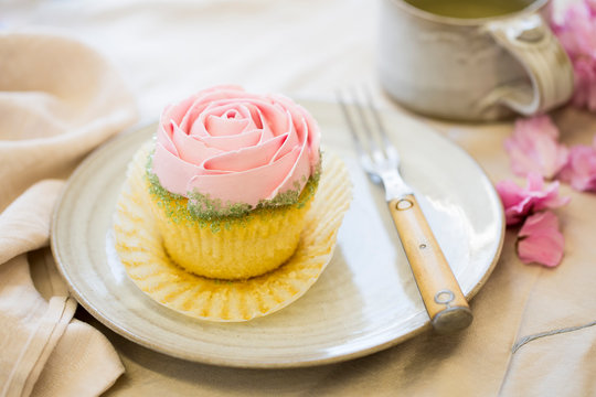 vanilla cupcake with pink frosting on plate