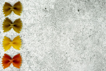 Types of uncooked pasta. Green, yellow and red pasta farfalle dry on a light concrete background. Shooting from above. Flat lay, top view, copy space