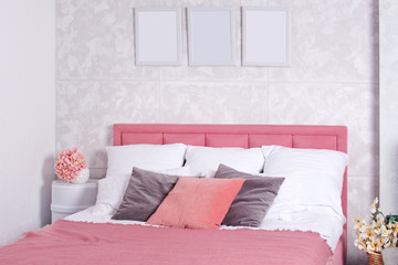 Stylish interior of modern bedroom. White and pink design of cozy bedroom with flowers. King-size bed with pink and grey bedding