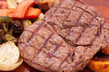 Meat grilled ribai with vegetables. Ribai steak on wooden board. Close up