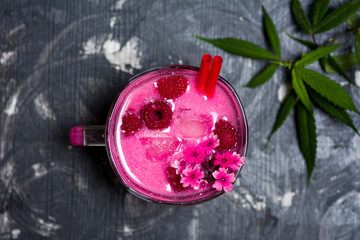 Raspberry smoothie in decorated glass with marijuana