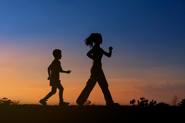 Fototapeta na wymiar Silhouette woman and boy active walking at sky sunset.background