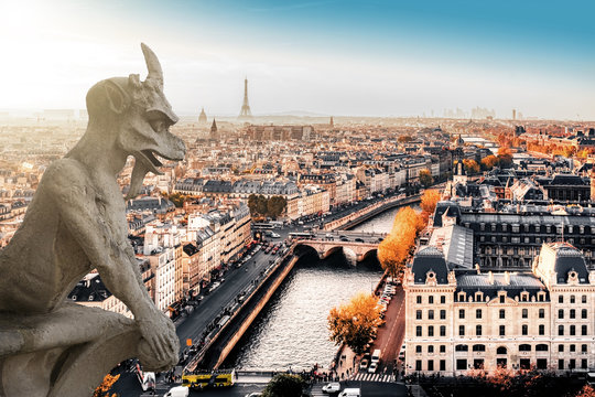 Famous Notre Dame gargoyle overlooking the Paris cityscape with Eiffel Tower in the background.