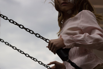 young beautiful girl in a pink blouse with flowers on her face takes off on a swing. outgoing childhood and adolescent problems.