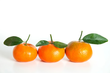 Close up image of three juicy organic whole tangerines with green leaves & visible zest texture, isolated white background, copy space. Macro shot of single bright citrus fruit. Top view, flat lay.