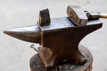 A hammer and a metal object on an anvil. Tools and metal objects used by the blacksmith in a blacksmith shop.