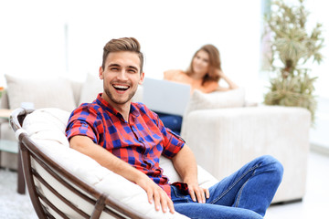 happy young man sitting in a big chair on blurred background