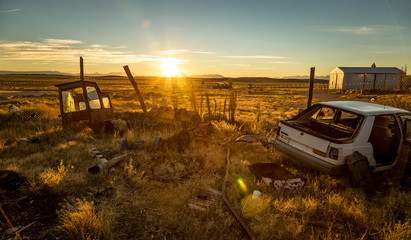 Fototapeta na wymiar scrap metal and old car polluting Patagonia in a colorful sunset