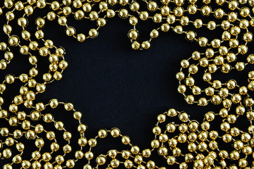 Christmas golden beads close-up on a black background. View from above.