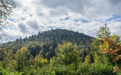 Beautiful autumn mountain forest landscape. Clouds over the rocks.