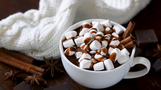 Hot chocolate. Woman hand put cup of hot chocolate with marshmallows on table. Christmas drink, comfort food concept