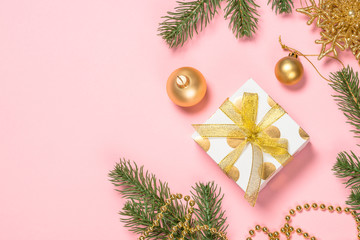 Golden Christmas flat lay background on pink with present box and decorations.