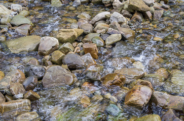 Beautiful mountain river with a fast flow. Large stones with rocks in the middle of a green forest.