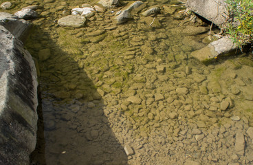 Beautiful mountain river with a fast flow. Large stones with rocks in the middle of a green forest.