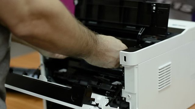 Men hands replacing toner cartridge in a modern laser printer